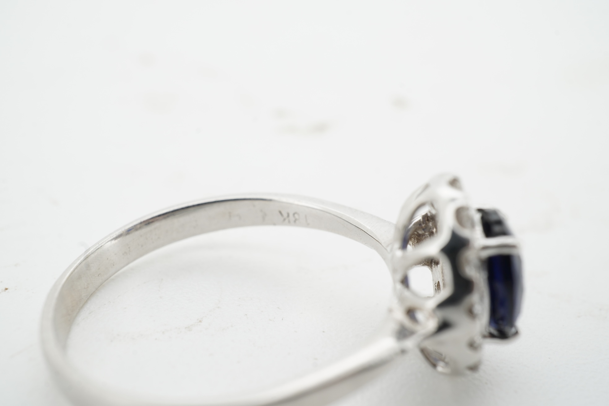 A synthetic sapphire and diamond cluster ring, mounted in white gold, size L1/2, stamped 18K, gross weight approximately 1.5 grams
